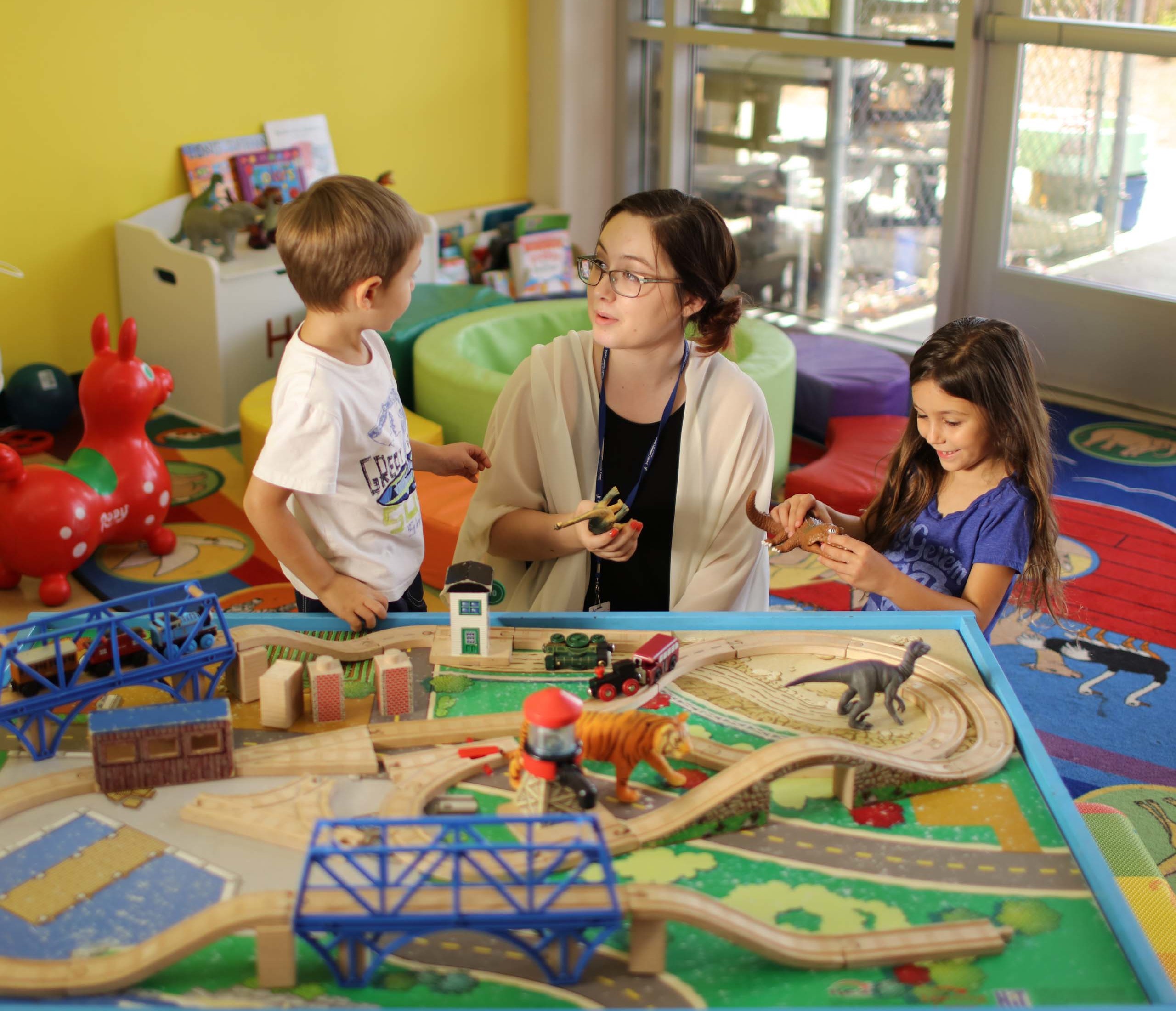 Two kids playing with toys alongside an adult.