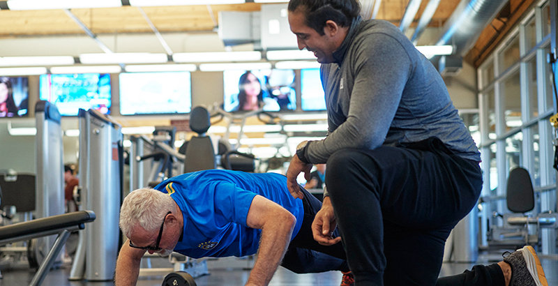 A man exercising with guidance from a personal trainer.